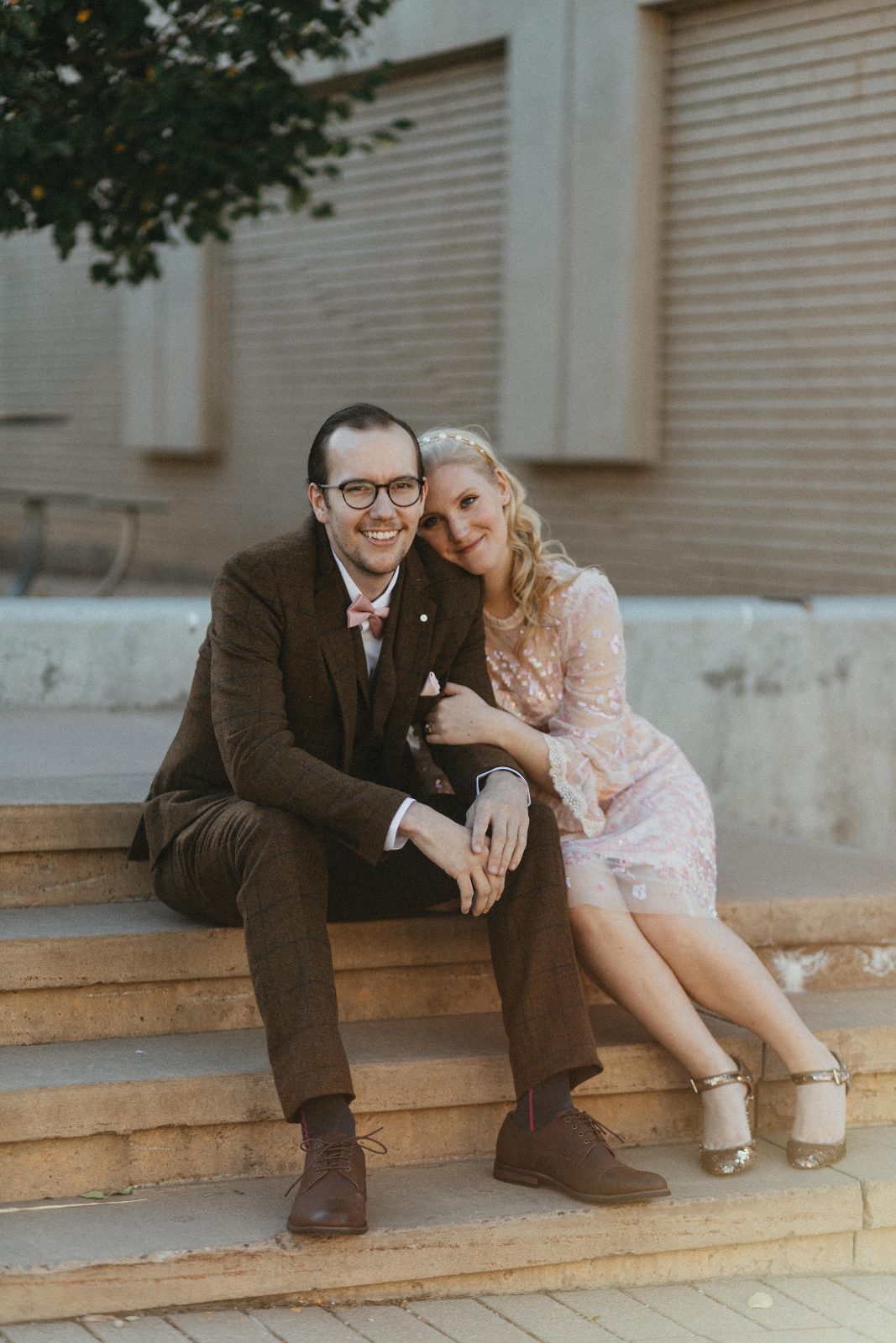 Engagement portrait of a couple snuggling on stone steps in front of a historic building