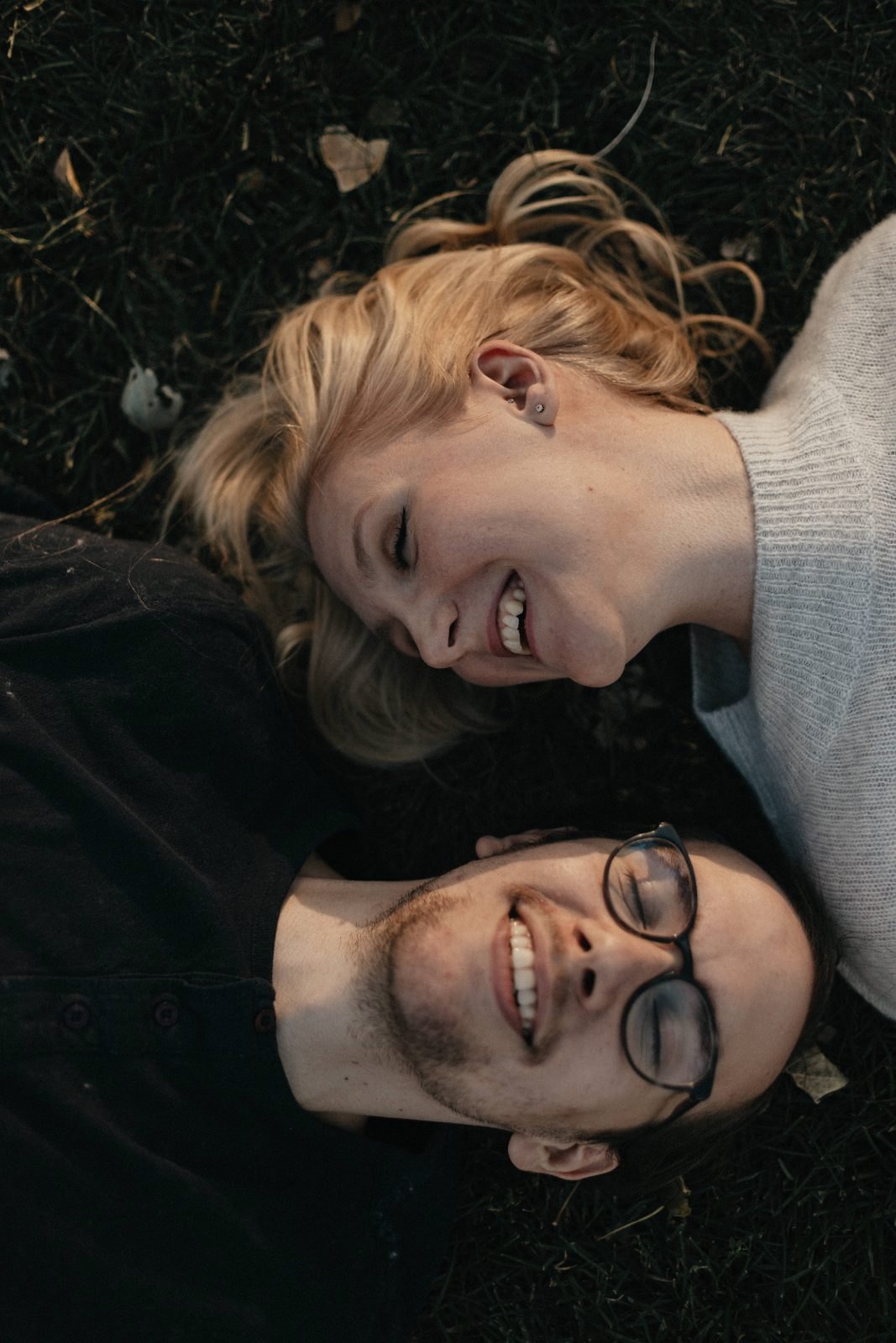 Overhead photo of a smiling couple lying side by side in the grass
