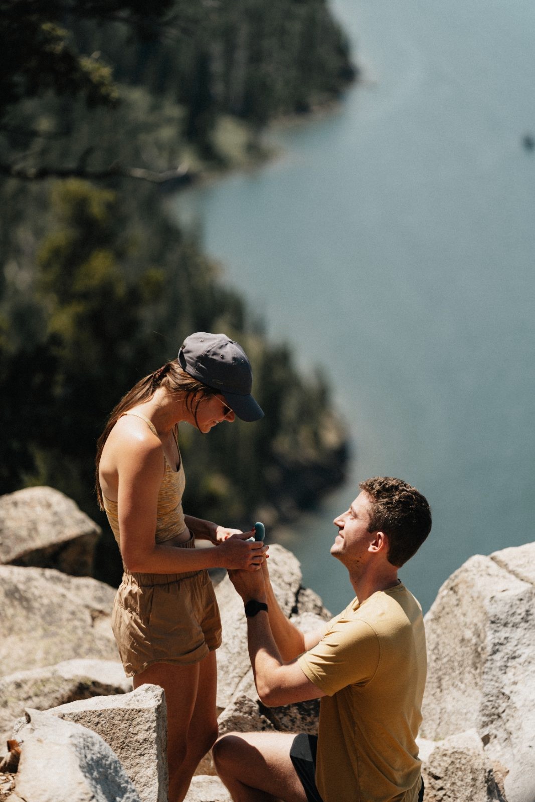Surprise proposal on a rocky cliff above a mountain lake