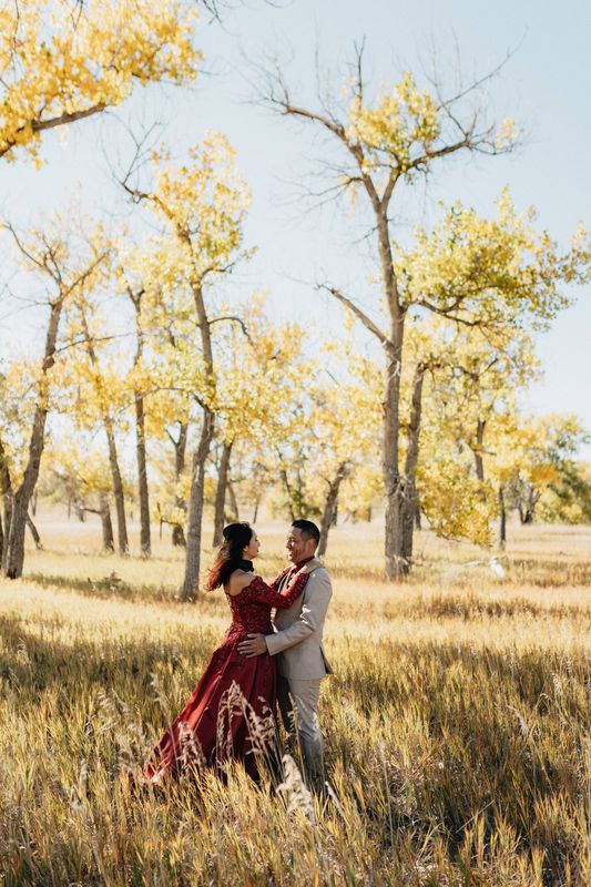Couple embracing in a golden meadow beneath autumn cottonwood trees