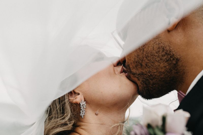Close-up of a bride and groom kissing beneath the bride's sheer veil