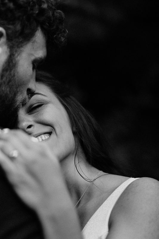 Black and white close-up of a laughing bride resting against her groom's shoulder