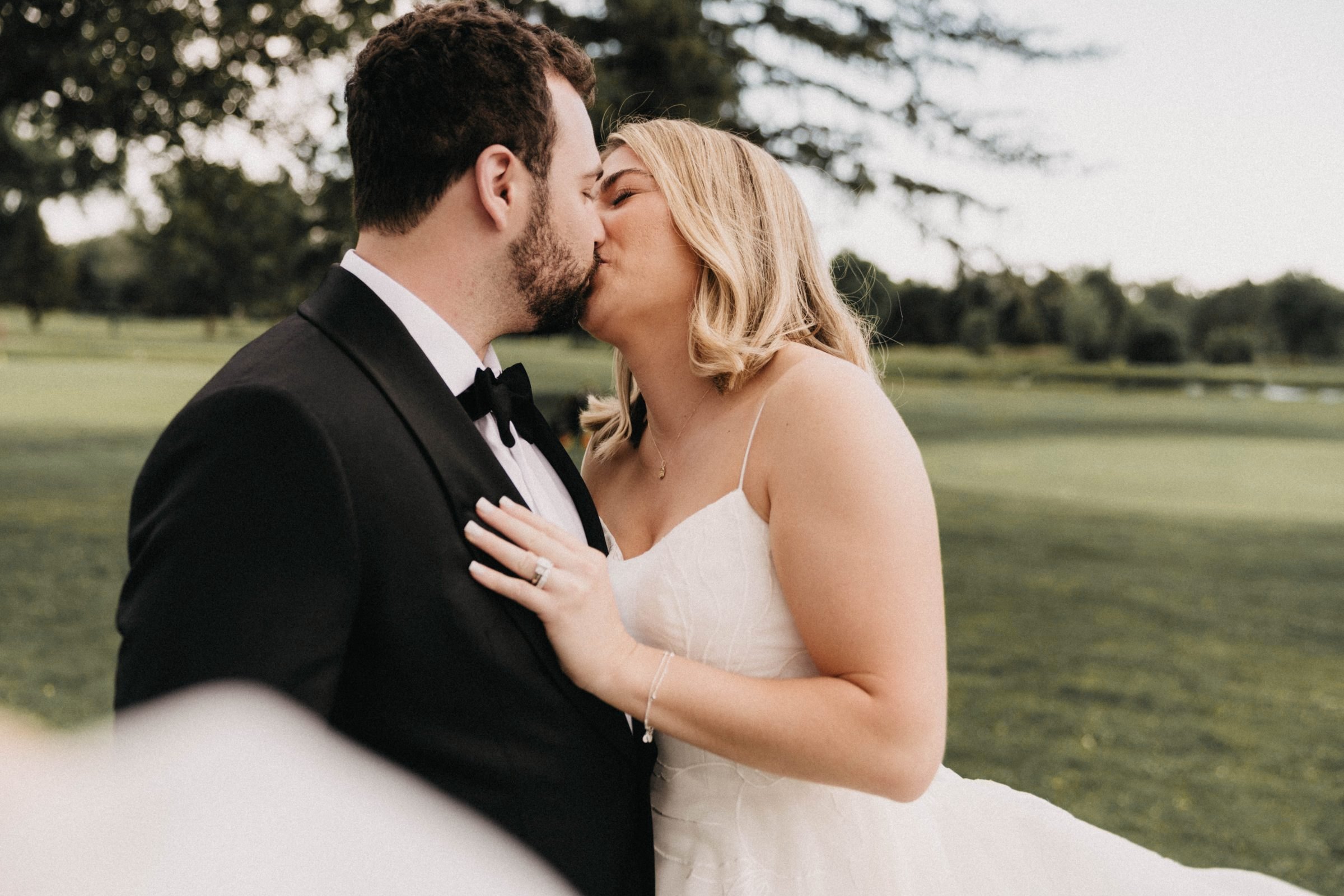 Bride and groom share a kiss on a golf course lawn