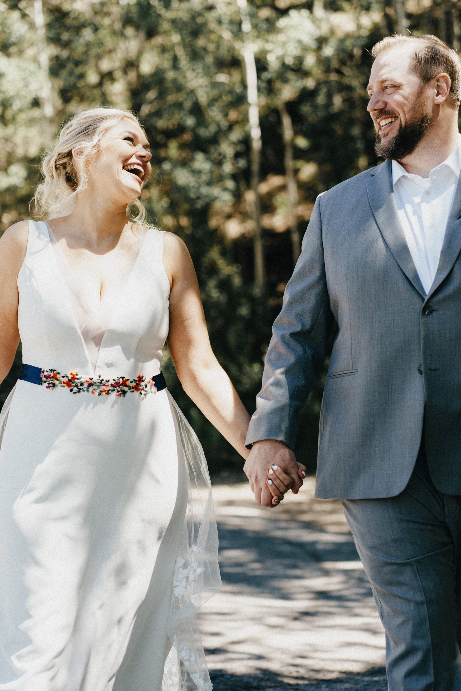 Bride laughing as she walks hand in hand with her groom through aspen trees