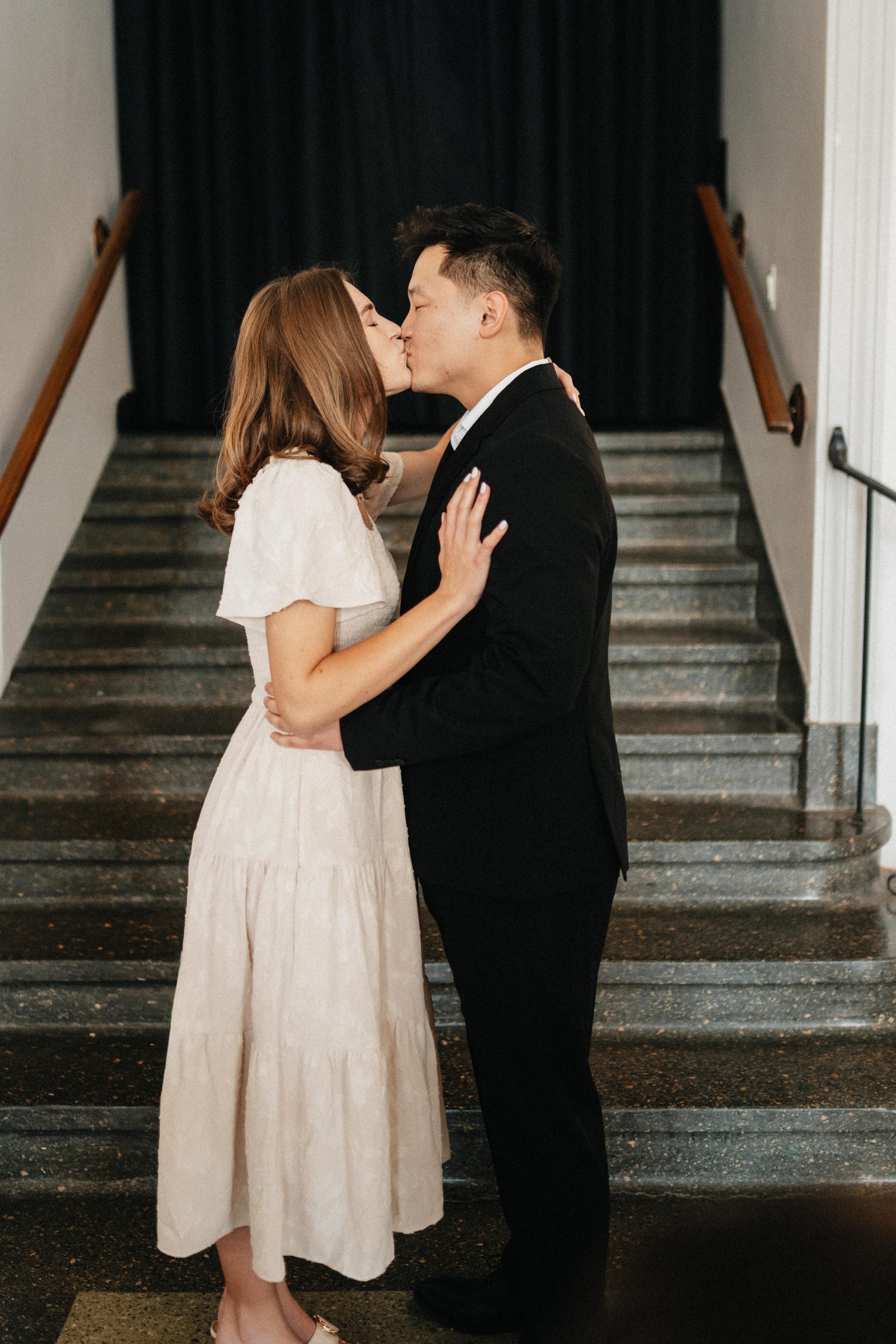 Couple kisses on a staircase in an elegant historic building